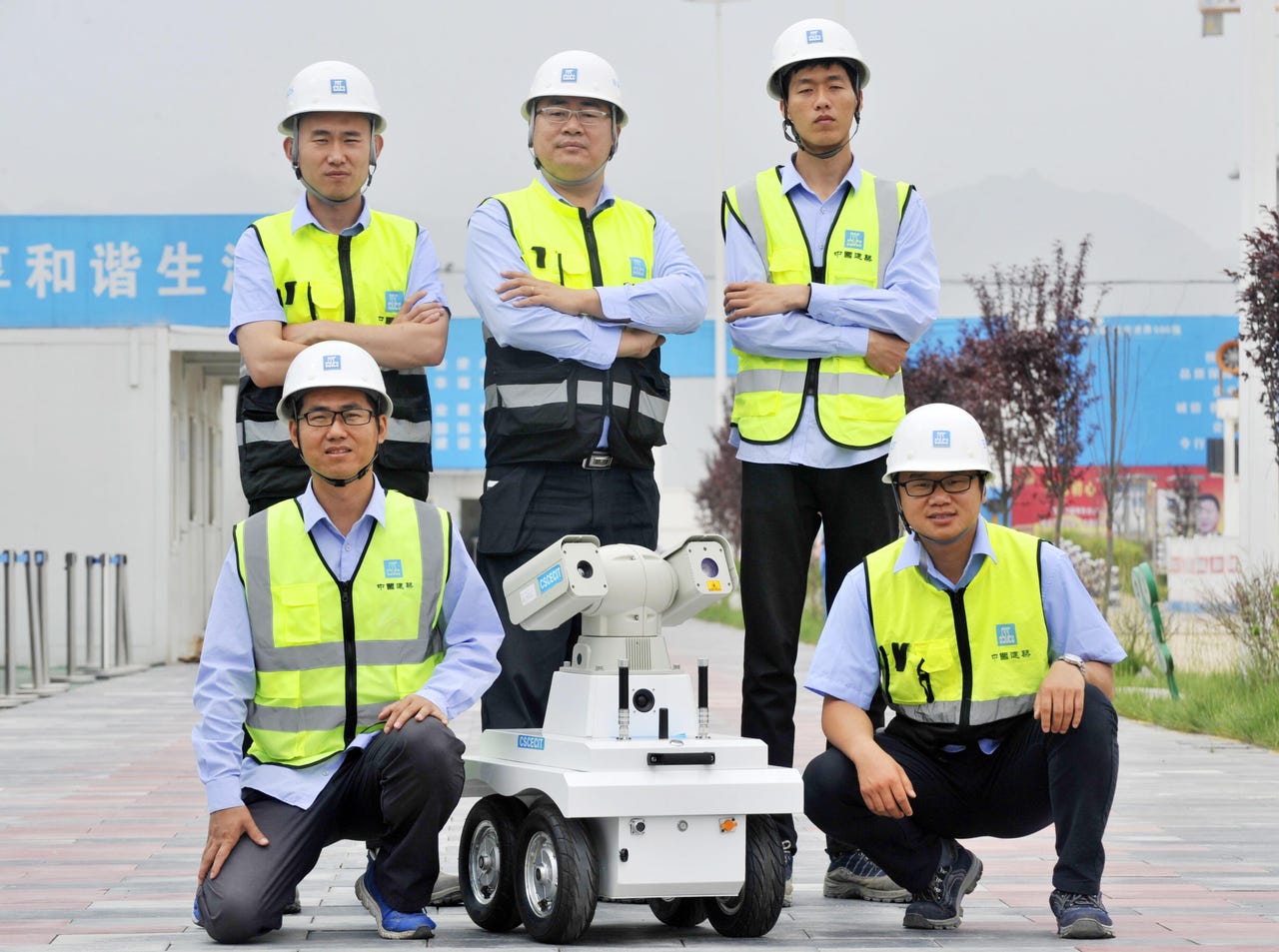 Cinq personnes en tenue de sécurité ont posé pour une photo d'équipe avec un robot d'inspection à roues.